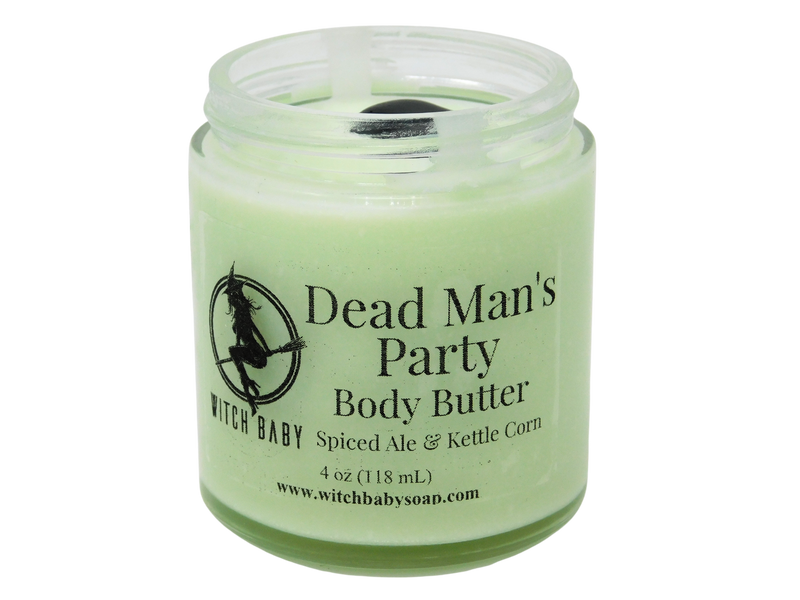 light ghoulish green body butter in 4 oz glass jar topped with black onyx. clear label reads: dead man's party body butter. spiced ale & kettle corn.