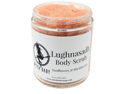 8 oz glass jar of light pink sugar scrub with white label that reads: Lughnasadh Body Scrub. Sunflowers & Blackberries.