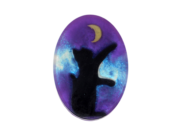 A purple oval shaped soap with a glitter galaxy background and a black cat sitting under a moon