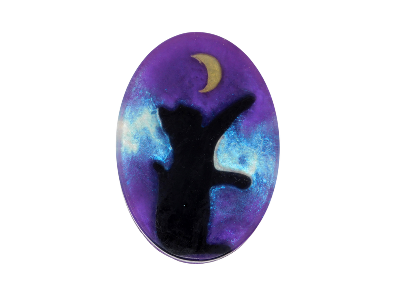 A purple oval shaped soap with a glitter galaxy background and a black cat sitting under a moon