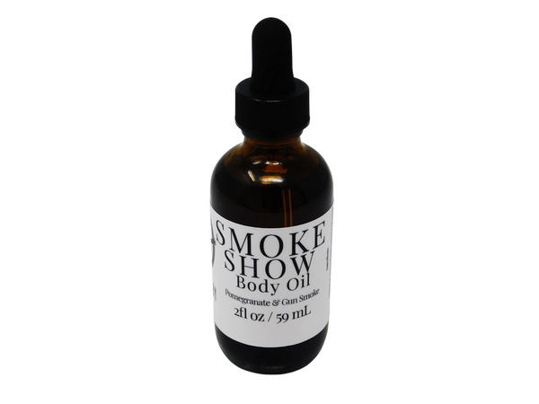 Smoke Show Body oil in a 2 oz glass dropper bottle with a white label that reads: Smoke Show Body Oil. Pomegranate & Gun Smoke.