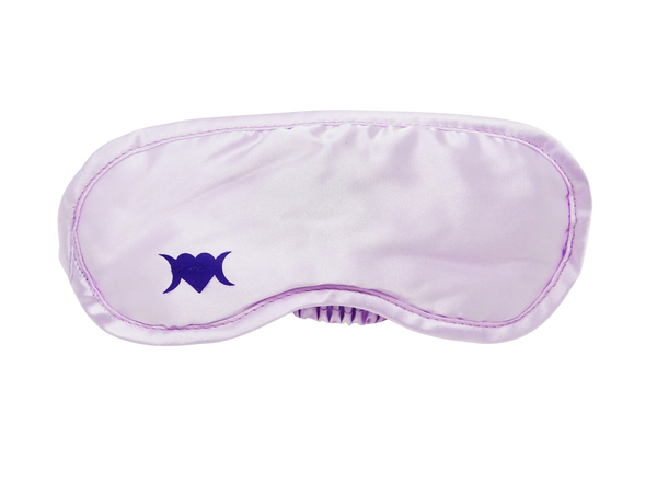 Photo of light lilac colored sleep mask with a symbol on the bottom left corner that is a heart with two crescent moons.