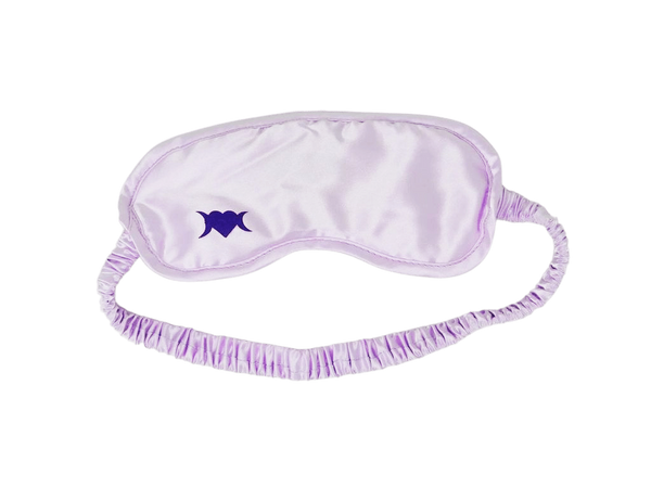 Photo of light lilac colored sleep mask with a symbol on the bottom left corner that is a heart with two crescent moons.